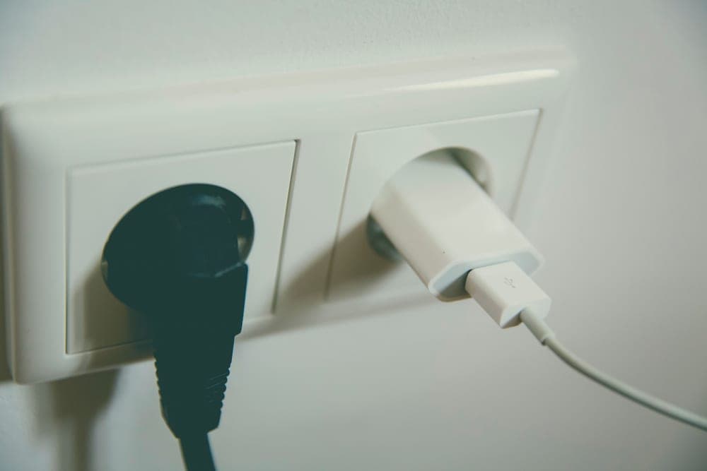 An electrical outlet and cord on a plain wall