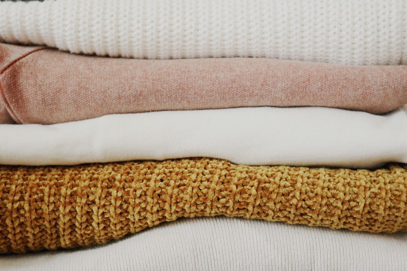 Folded stacks of linen and wool fabric in warm daylight