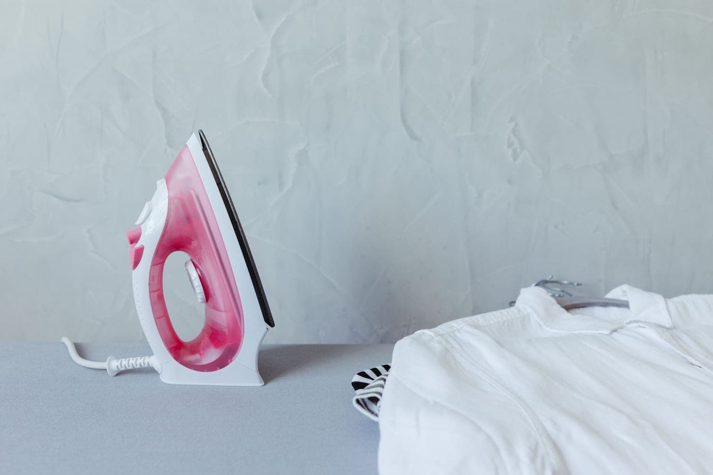 An iron resting on an ironing board beside a folded shirt