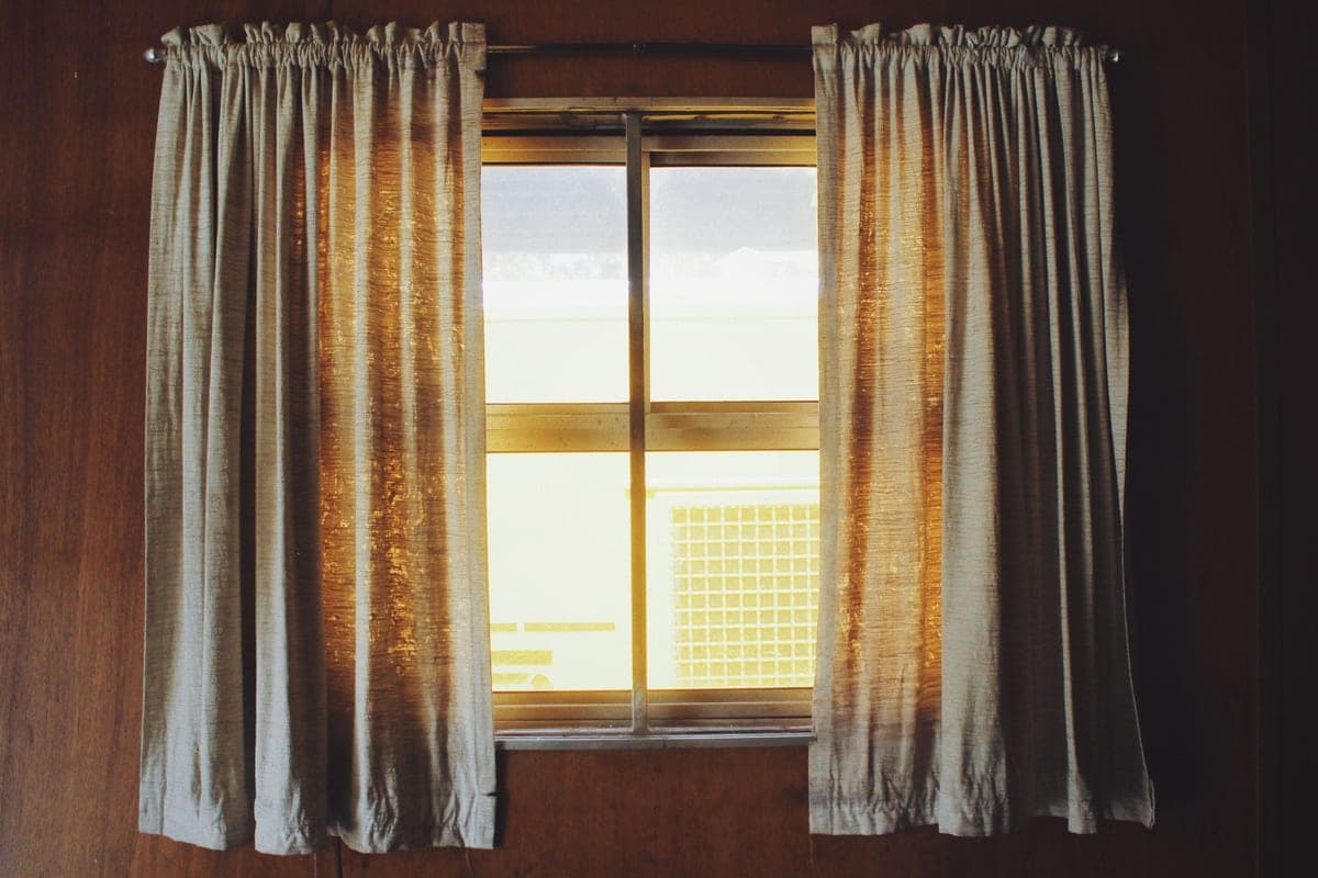 Long curtains hanging beside a bright window