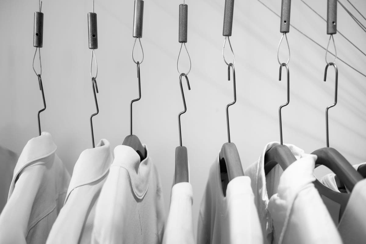 Crisp white shirts hanging on wooden hangers