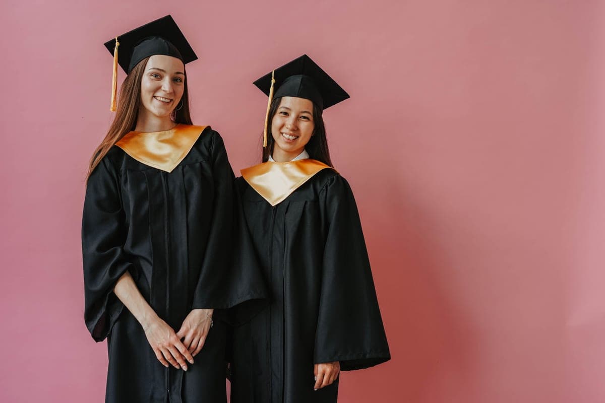 A graduation gown and mortarboard cap laid out