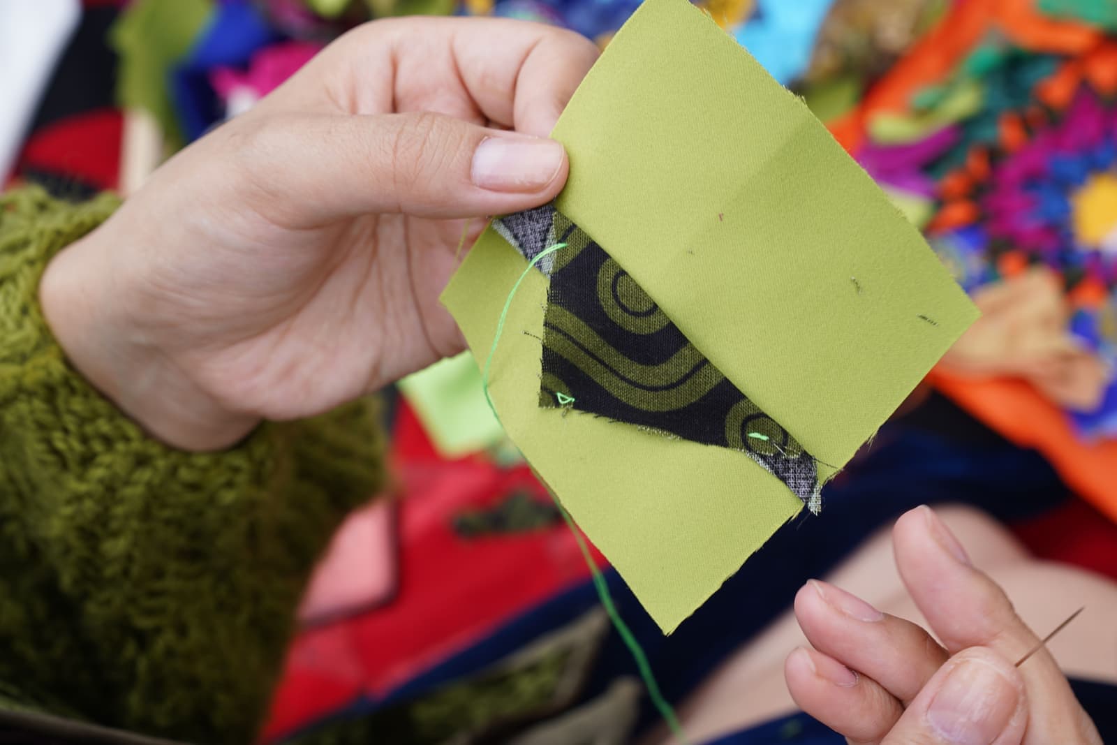 Hands quilting with brightly patterned fabric squares