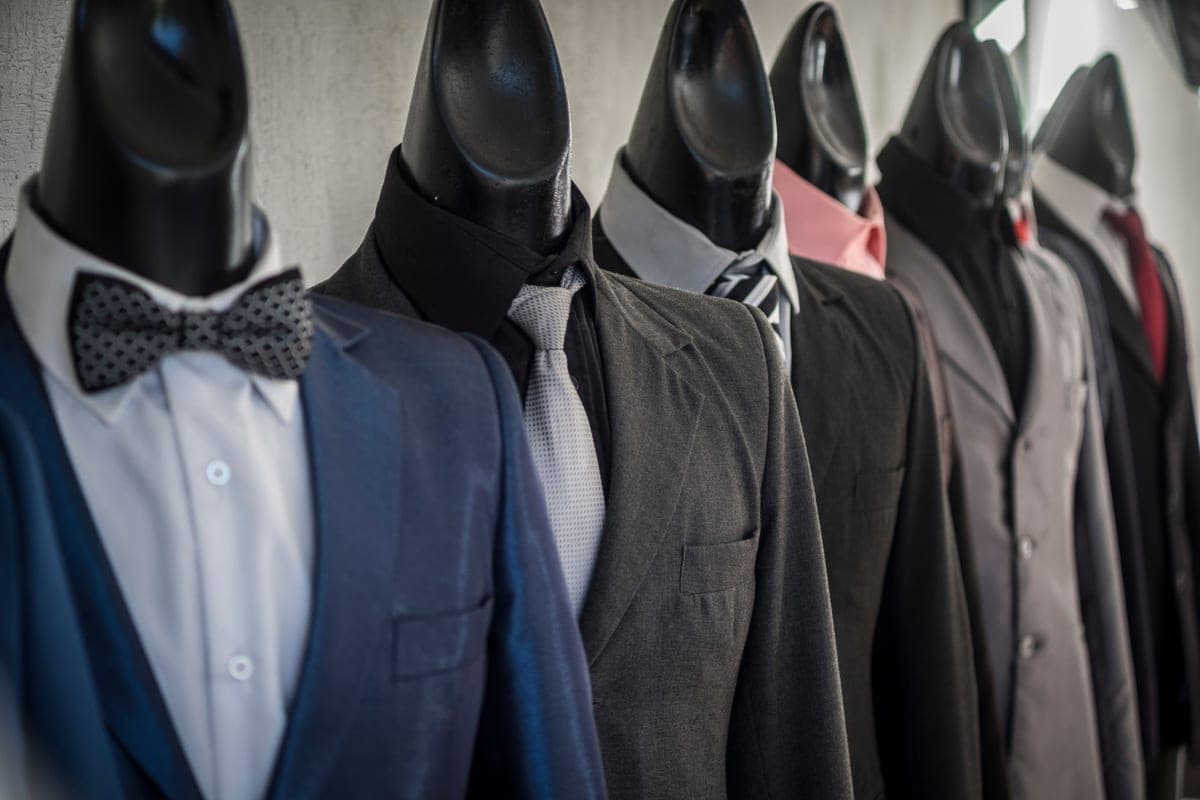 A tailored suit jacket and tie laid out on a bed