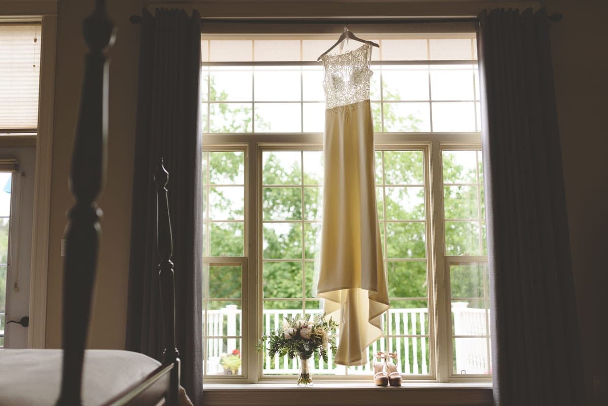 A long white dress hanging by a window in daylight